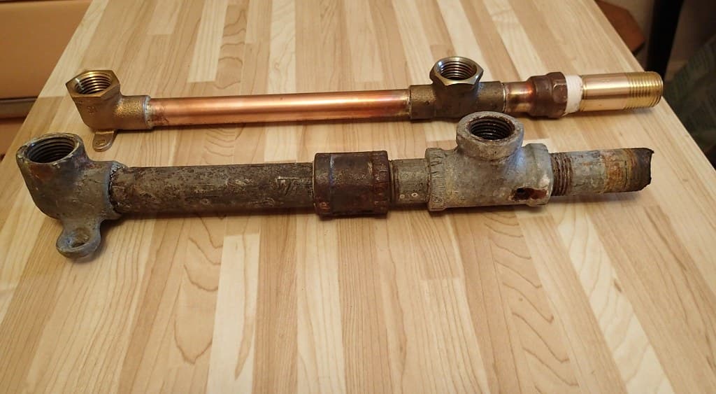 Old corroded pipe next to new copper pipe, a repipe comparison